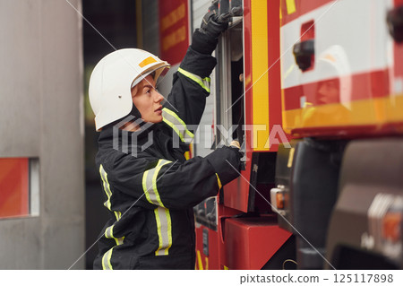 Taking equipment from the truck. Woman firefighter in uniform is at work in department Taking equipment from the truck. Woman firefighter in uniform is at work in department 125117898