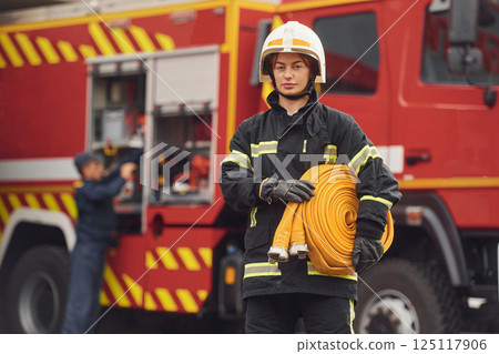 Holding fire hose. Woman in uniform is at work in department Holding fire hose. Woman in uniform is at work in department 125117906