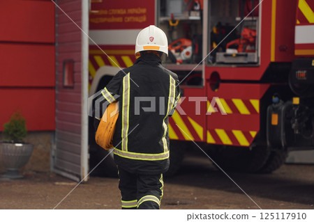 With fire hose in hands. Woman in uniform is at work in department With fire hose in hands. Woman in uniform is at work in department 125117910