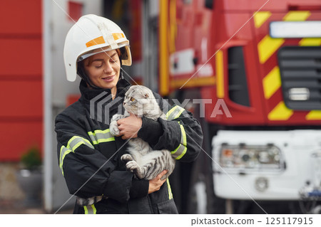 Holding beautiful scottish fold cat. Woman firefighter in uniform is at work in department Holding beautiful scottish fold cat. Woman firefighter in uniform is at work in department 125117915