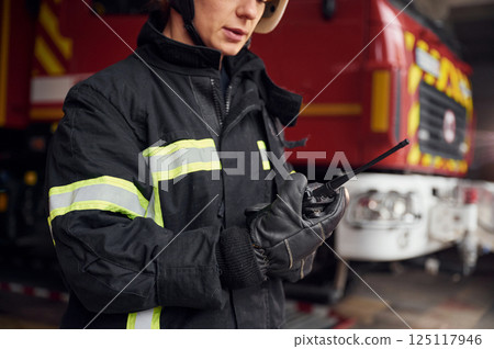 Using radio transmitter. Woman firefighter in uniform is at work in department Using radio transmitter. Woman firefighter in uniform is at work in department 125117946