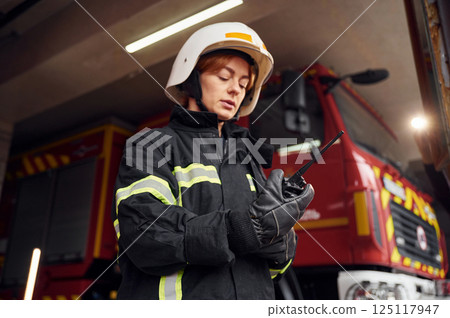 Using radio transmitter. Woman firefighter in uniform is at work in department 125117947