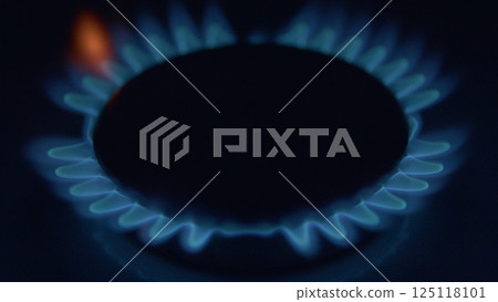 The illuminated flames from a gas burner create a mesmerizing ambiance against a dark background The illuminated flames from a gas burner create a mesmerizing ambiance against a dark background 125118101