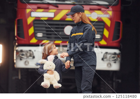 Against big truck. With bunny toy. Firefighter woman in uniform is with a little girl 125118480