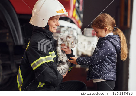 Rescued scottish fold cat. Firefighter woman in uniform is with a little girl Rescued scottish fold cat. Firefighter woman in uniform is with a little girl 125118486