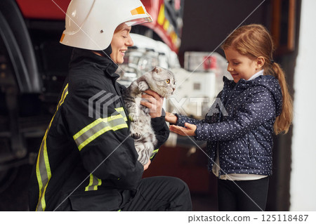 Rescued scottish fold cat. Firefighter woman in uniform is with a little girl 125118487