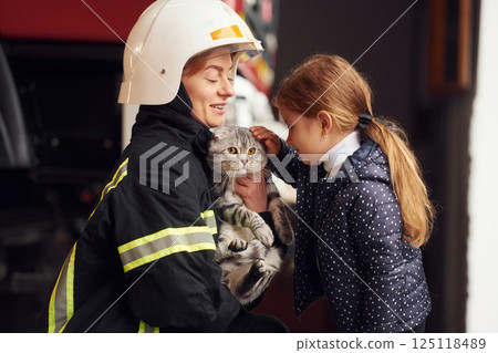 Rescued scottish fold cat. Firefighter woman in uniform is with a little girl 125118489
