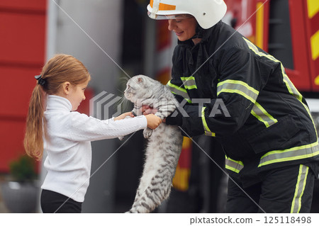 Giving scottish fold cat to the owner. Firefighter woman in uniform is with a little girl 125118498