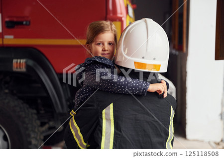 Embracing her hero. Firefighter woman in uniform is with a little girl Embracing her hero. Firefighter woman in uniform is with a little girl 125118508