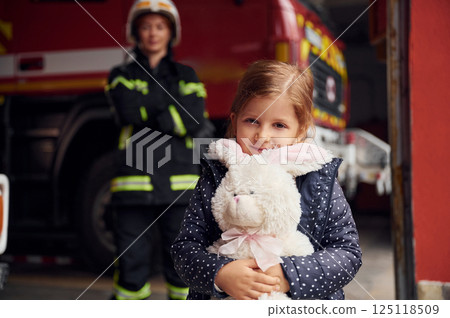 Kid is holding bunny toy. Firefighter woman in uniform is with a little girl Kid is holding bunny toy. Firefighter woman in uniform is with a little girl 125118509