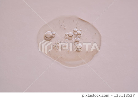 Textured drop of serum with bubbles on pink background. Textured drop of serum with bubbles on pink background. 125118527