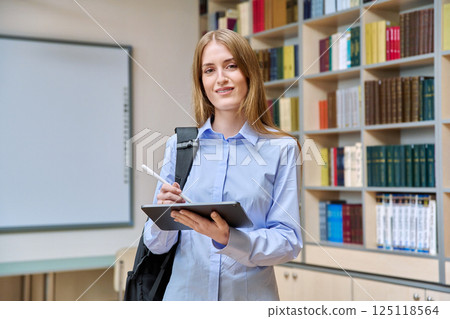 Portrait of student teenager girl using digital tablet inside classroom library Portrait of student teenager girl using digital tablet inside classroom library 125118564