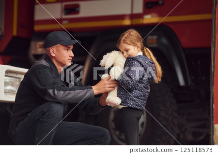 With little bunny toy. Firefighter man is with little girl at department 125118573