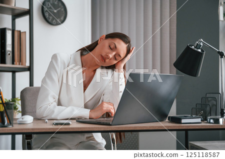 Feeling tired, having headache. Young beautiful woman in formal clothes is working at office 125118587