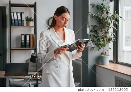 Reading document in notepad. Young beautiful woman in formal clothes is working at office Reading document in notepad. Young beautiful woman in formal clothes is working at office 125118605
