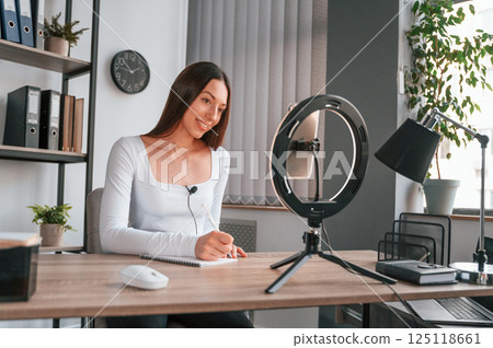 Professional lighting. Online master class. Young beautiful woman in white clothes is in the office 125118661