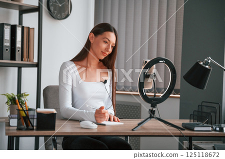 Online education. Young beautiful woman in white clothes is in the office 125118672