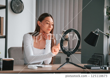 Online education. Young beautiful woman in white clothes is in the office Online education. Young beautiful woman in white clothes is in the office 125118673