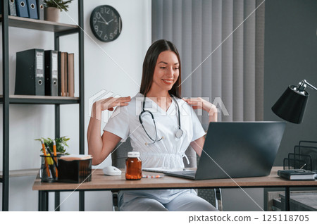 Doing online consultation. Young beautiful female doctor in white coat is in the office Doing online consultation. Young beautiful female doctor in white coat is in the office 125118705