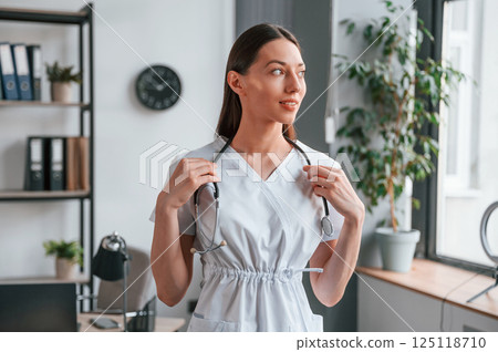 Portrait of young beautiful female doctor in white coat that is in the office Portrait of young beautiful female doctor in white coat that is in the office 125118710