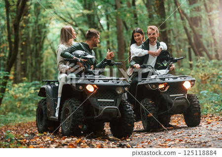Man showing thumb up. Two couples on a quad bike in the forest during the day 125118884