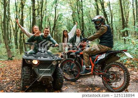 Two couples on ATV with man that is on the bike in the forest that looking at the camera 125118894