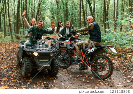 Two couples on ATV with man that is on the bike in the forest 125118898