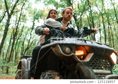 Close up view of another transport. Young couple riding a quad bike in the forest 125118957