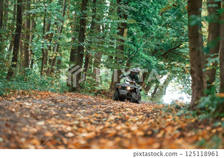 Driving on the footpath. Young couple riding a quad bike in the forest Driving on the footpath. Young couple riding a quad bike in the forest 125118961