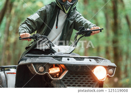 Front view. ATV driver is in the forest, having a ride at daytime Front view. ATV driver is in the forest, having a ride at daytime 125119008