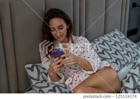 Woman Smartphone Bed Relaxation: Indoor leisure, using mobile phone in bed, daytime. 125119174
