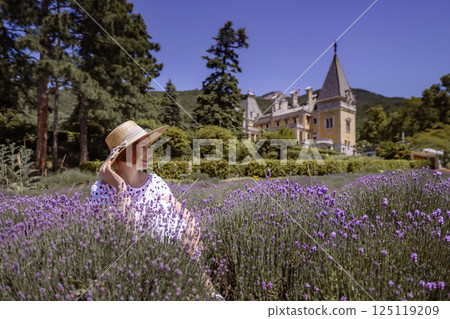 A woman is sitting in a field of purple flowers A woman is sitting in a field of purple flowers 125119209