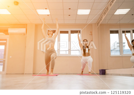 Two beautiful women do yoga, sports in the gym. The concept of grace and beauty of the body. Two beautiful women do yoga, sports in the gym. The concept of grace and beauty of the body. 125119320