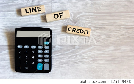 there is a calculator and wooden blocks with the inscription "CREDIT LINE". Workplace close-up. there is a calculator and wooden blocks with the inscription "CREDIT LINE". Workplace close-up. 125119428