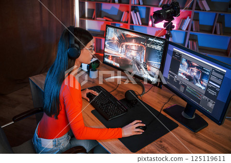 Focused on the game process. Young beautiful streamer is indoors with pc 125119611