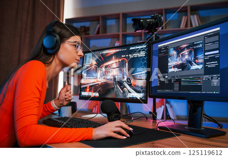 Focused on the game process. Young beautiful streamer is indoors with pc 125119612