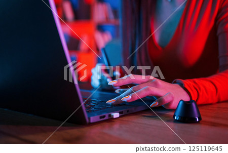 Young female retoucher working with computer and graphic tablet in neon lighting office 125119645
