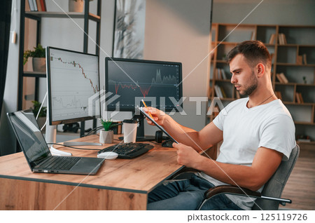 Laptop is on the table. Young stock broker is working in the office by using computer Laptop is on the table. Young stock broker is working in the office by using computer 125119726