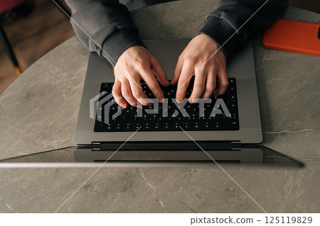 Close-up top view of unrecognizable freelancer male remote working from home office, developing software solutions, sitting at table by window in dark room. Concept of remote job, technology, people. 125119829