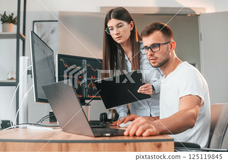 Analyzing information from computer screens. Two stock brokers is working together in the office with finances 125119845
