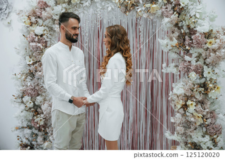 Holding by the hands. A young groom with his bride in a white dress. Wedding conception Holding by the hands. A young groom with his bride in a white dress. Wedding conception 125120020