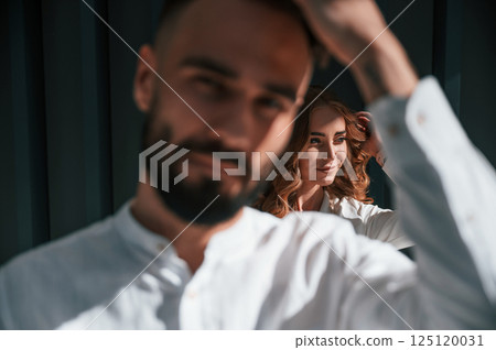 Beautiful young couple is standing together against dark green background 125120031