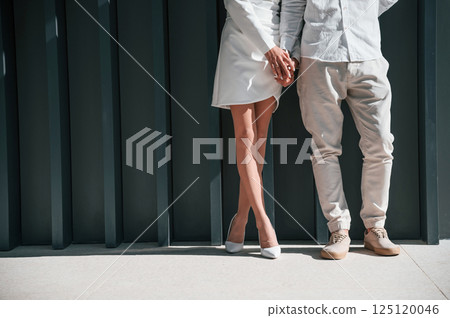 Close up view. Beautiful young couple is standing together against dark green background Close up view. Beautiful young couple is standing together against dark green background 125120046