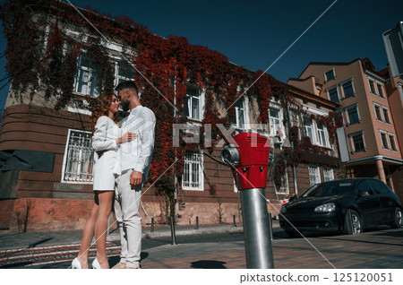 Embracing each other. Beautiful young couple is together on the street against old building 125120051