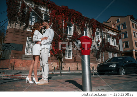 Embracing each other. Beautiful young couple is together on the street against old building 125120052