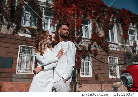 Embracing each other. Beautiful young couple is together on the street against old building Embracing each other. Beautiful young couple is together on the street against old building 125120054