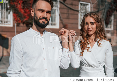 Showing the hands. Beautiful young couple is together on the street against old building 125120065