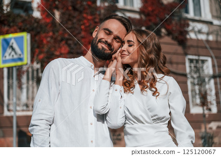 Embracing each other. Beautiful young couple is together on the street against old building 125120067