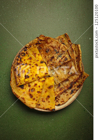 Delicious Indian naan flatbreads served on a plate on green background top view 125120100