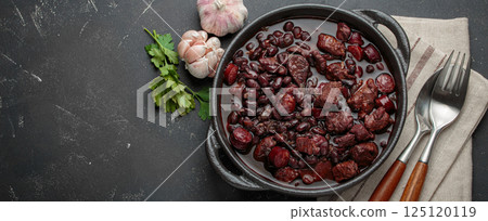 Brazilian feijoada with black beans, sausage and meat in a pot, top view with space for text Brazilian feijoada with black beans, sausage and meat in a pot, top view with space for text 125120119